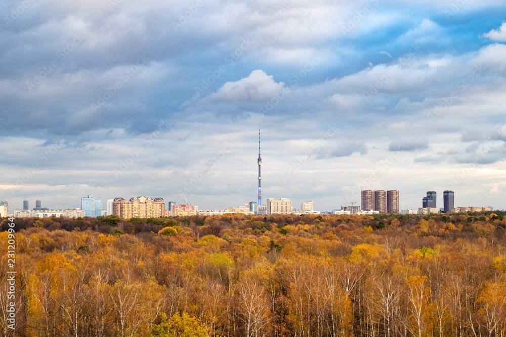 blue snow clouds over city and autumn forest