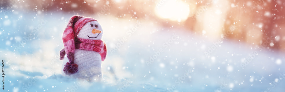 little knitted snowmans on soft snow on blue background