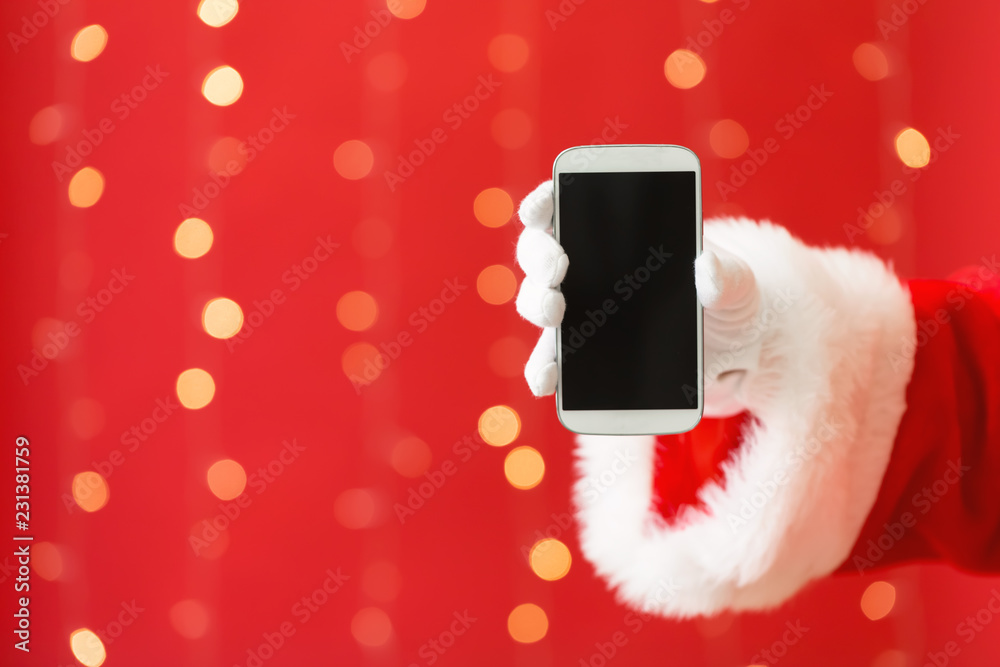 Santa holding a smartphone on a shiny light red background