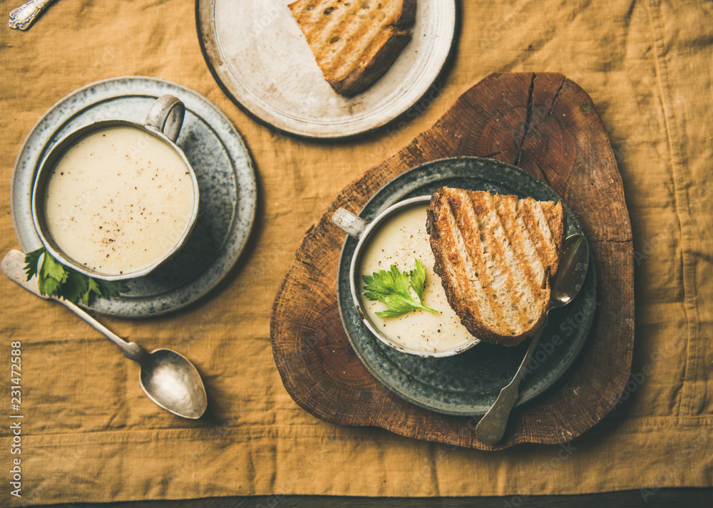 Autumn, Winter home dinner. Flat-lay of Fall warming celery cream soup in cups and grilled bread ove