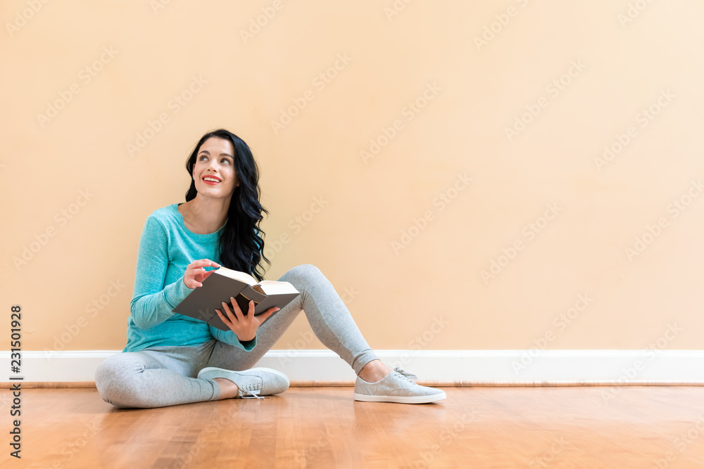 Young woman with a book against a big interior wall