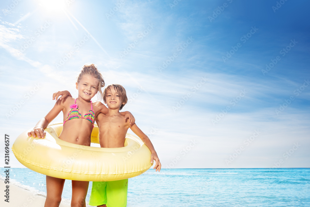 Funny kids in with swimming tube on the beach