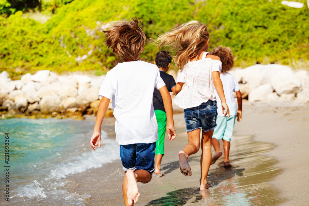 Kids running away along sandy beach in summer