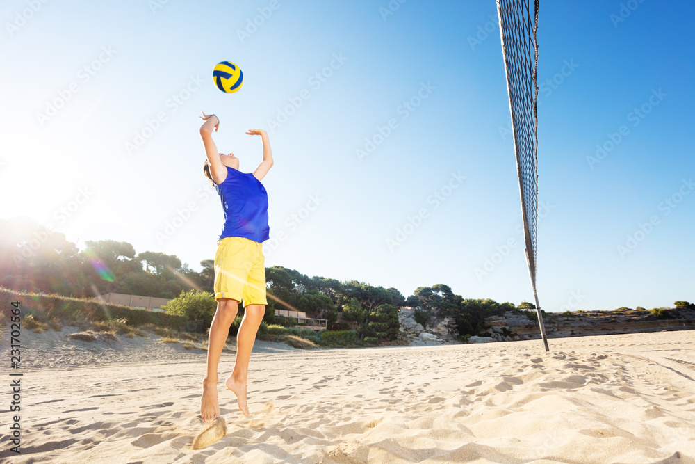 Young volleyball player jump serving on the beach