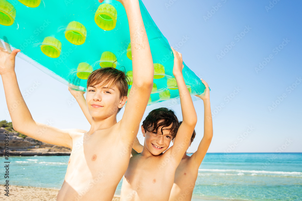 Happy boys carrying big air mattress together