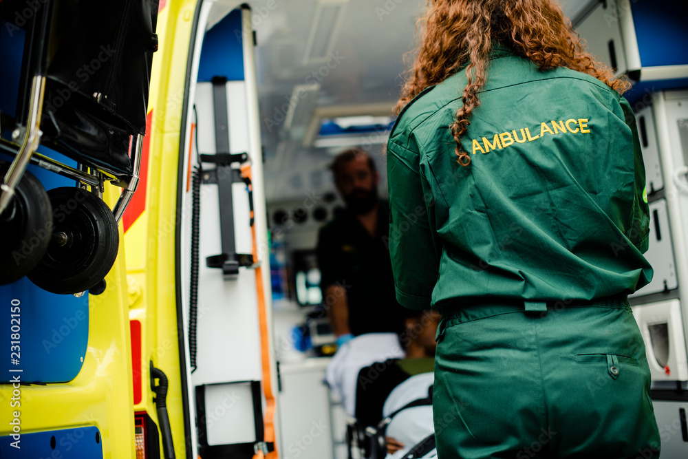 Paramedics moving a patient on a stretcher into an ambulance