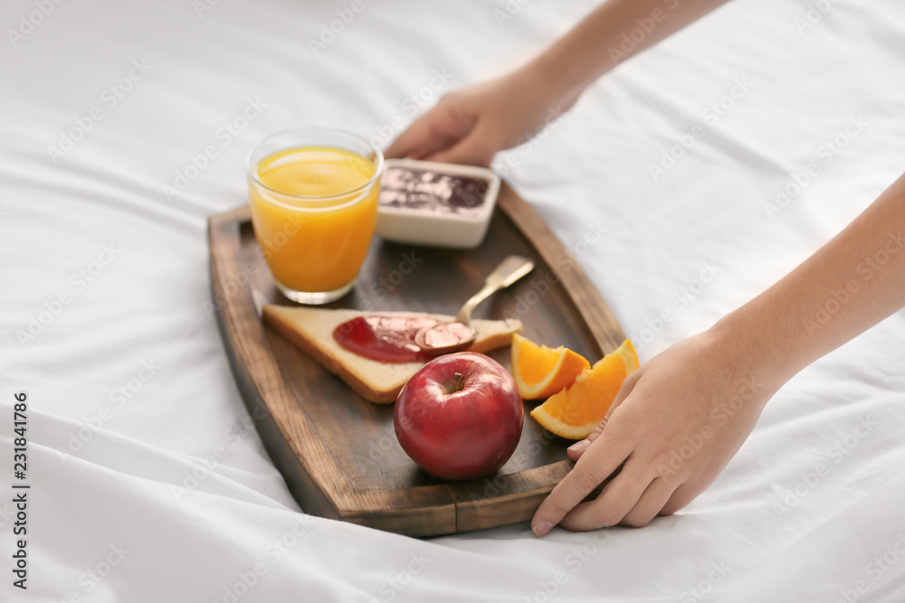 Young woman having delicious breakfast on bed