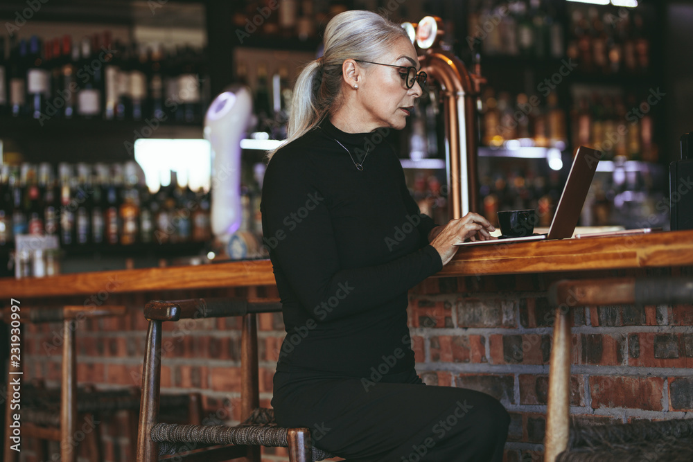 Mature business woman at coffee shop with laptop