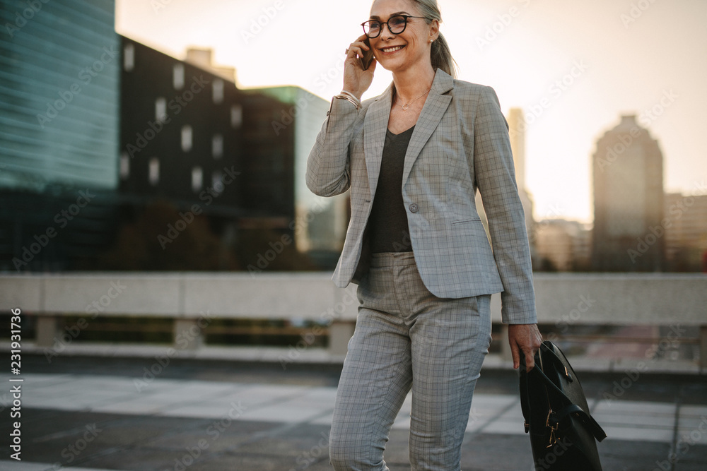 女商人拿着手机走在城市街道的户外