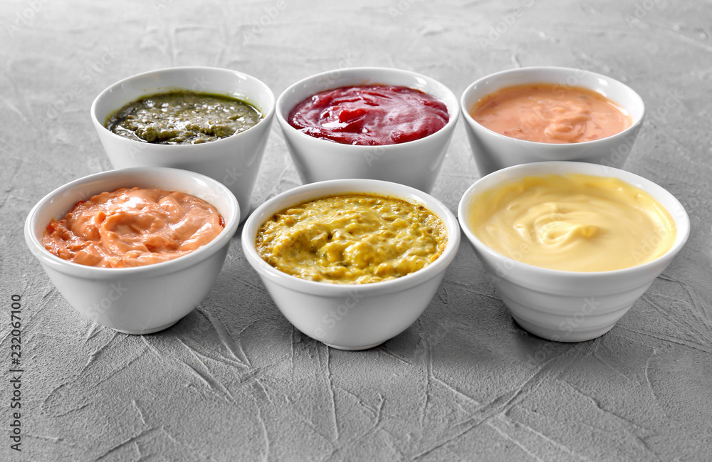 Different tasty sauces in bowls on grey background