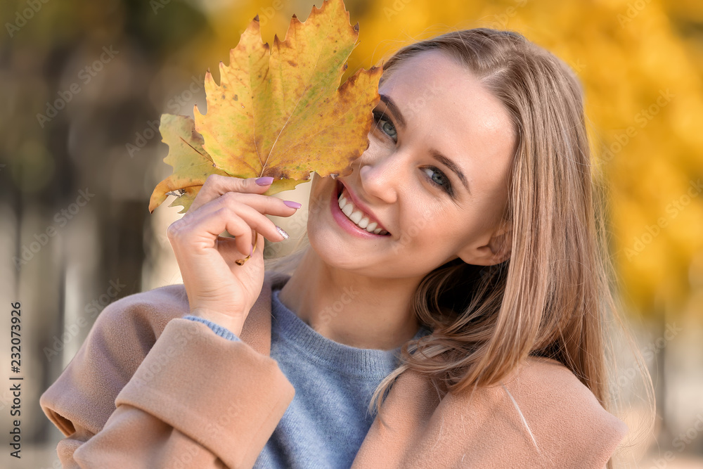 Beautiful young woman with autumn leaves in park