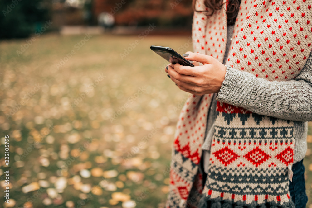 Text messaging outdoors in the autumn. Close-up.