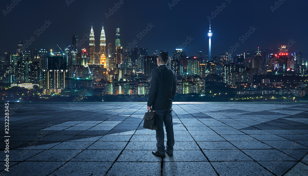 以现代城市天际线为背景，以夜景为背景的商人的目光和思考。