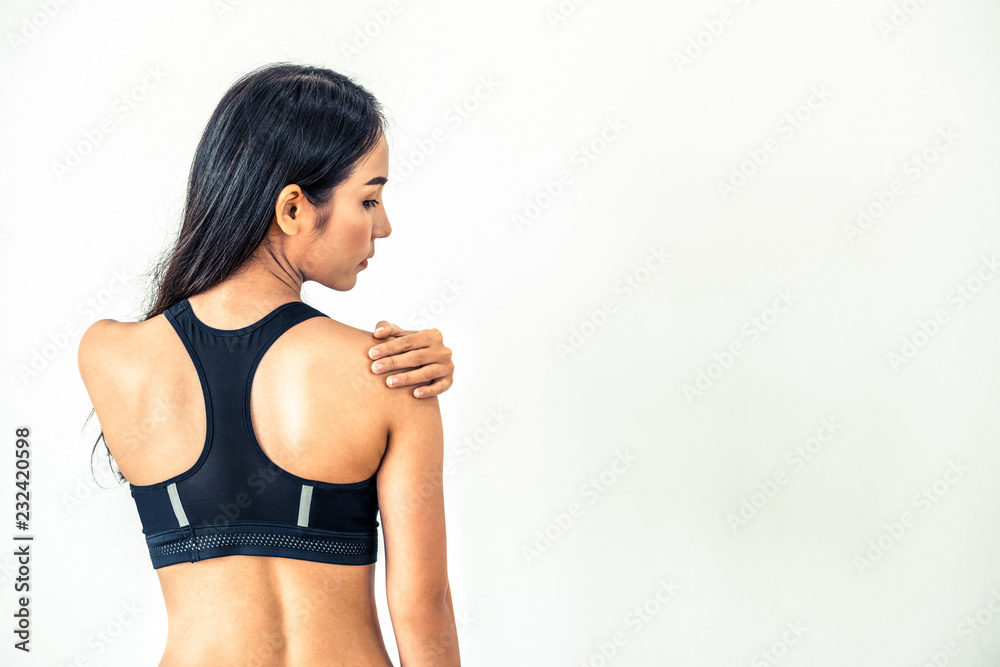 Sporty woman touching shoulder in fitness gym. Healthy lifestyle concept.