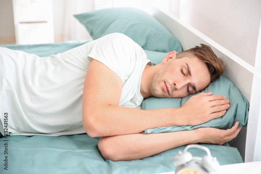 Handsome man sleeping in bed at home