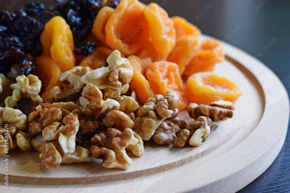 Useful dried fruits and walnuts on wooden background.