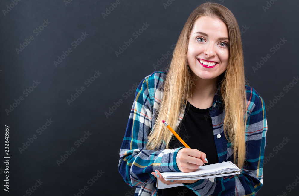 黑底带笔记本和铅笔的年轻女子