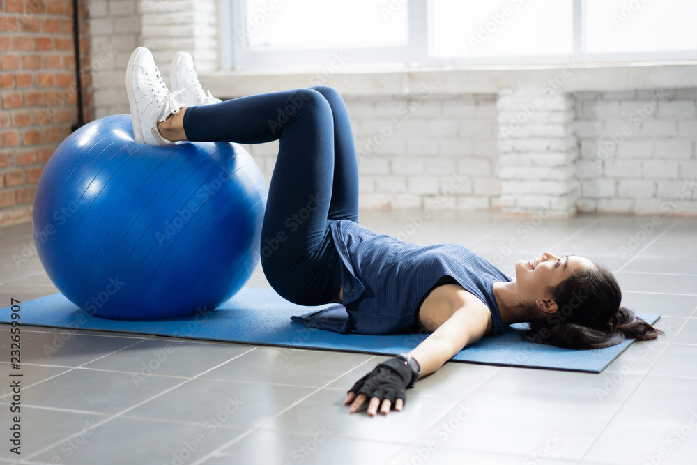 Asian women using an exercise ball in her house.