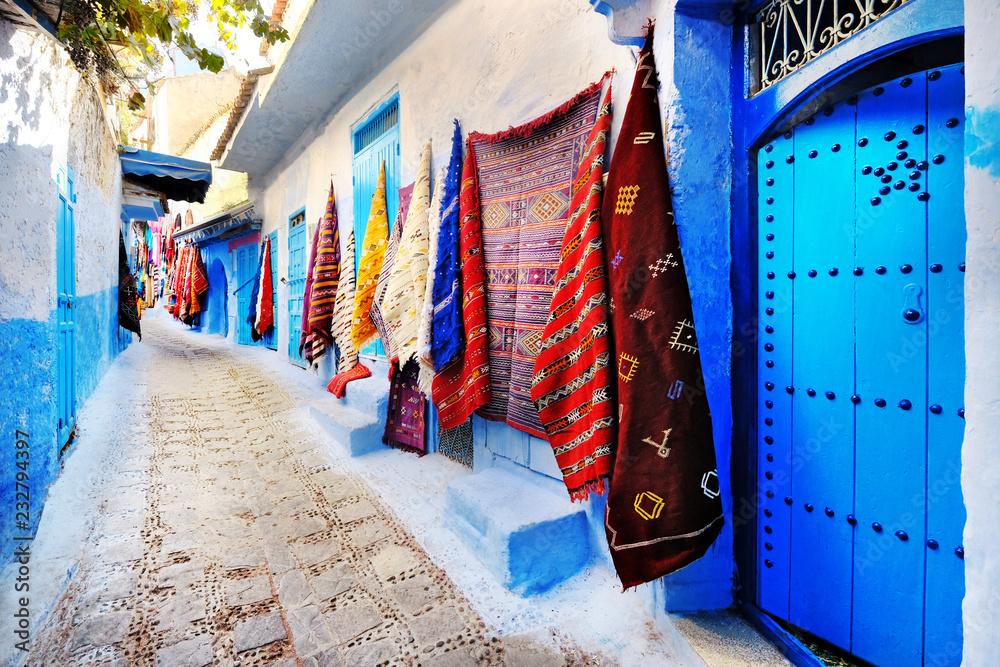 Moroccan handmade crafts, carpets and bags hanging in the narrow street of Essaouira in Morocco with