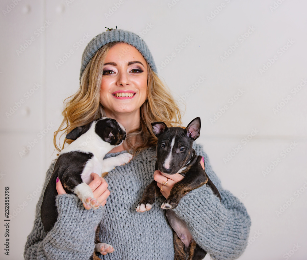 一个快乐美丽的女孩拥抱着小狗。两只有趣的小斗牛犬在一只漂亮的小狗手里