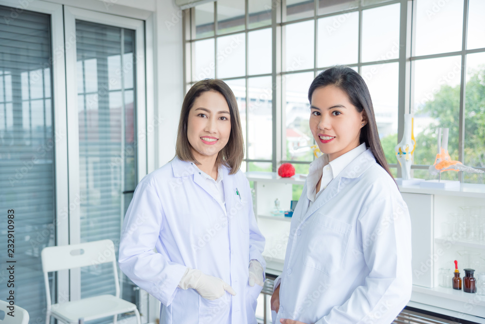 Beautiful asian medical student standing with young female medical professional teacher in classroom