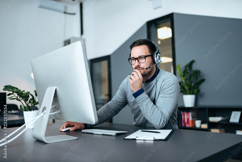 Concerned male customer support operator working in his office.