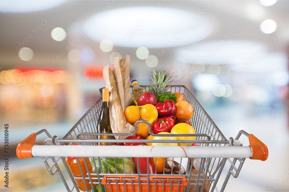 Shopping cart filled with various groceries in store