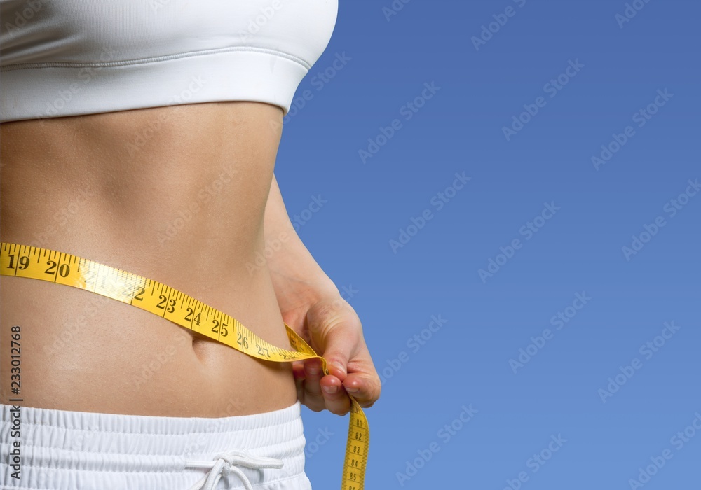 Slim young woman measuring her thin waist with a tape measure