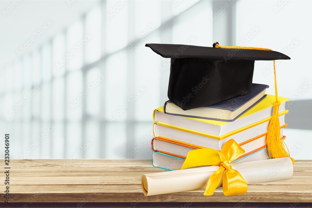 Graduation mortarboard on top of stack of books on  background