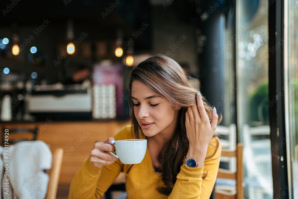 Stylish young woman drinking coffee at the cafe.