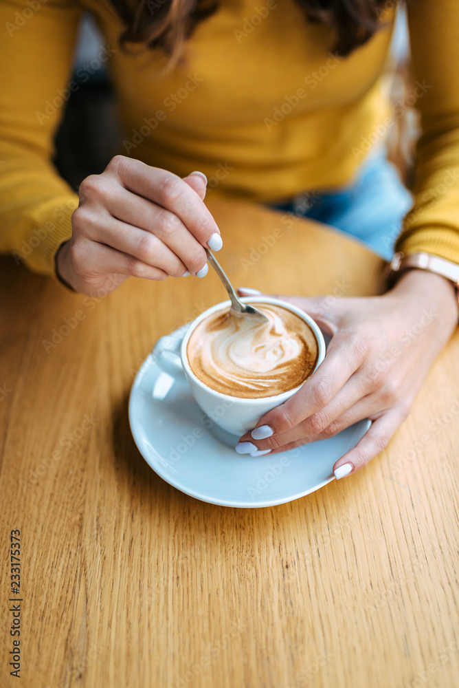 Female hands with latte on a wooden table.