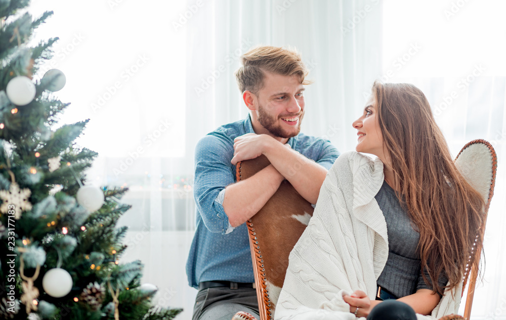 Couple in love celebrating Christmas together at home next to Xmas tree