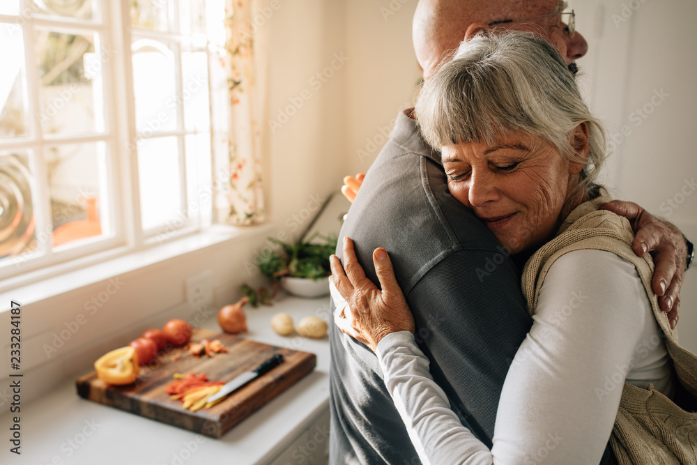 Senior man and woman embracing standing at home