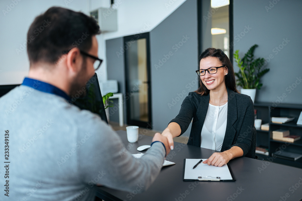 女商人和商人在现代办公室握手。