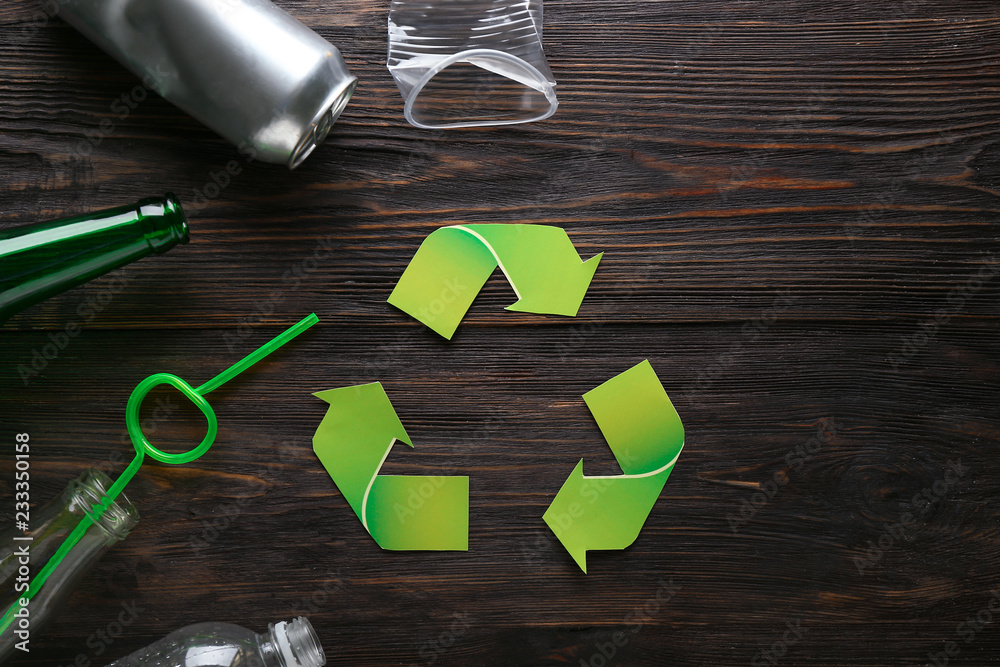 Different garbage with symbol of recycling on wooden background. Ecology concept