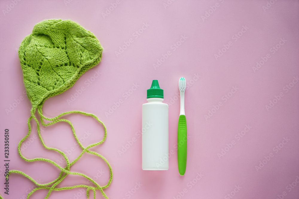 Cosmetics with toothbrush and knitted hat on color background