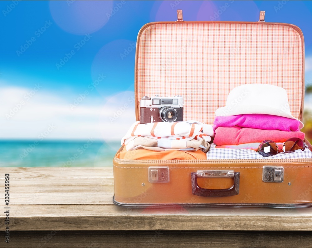 Retro luggage with colorful clothes on blurred background