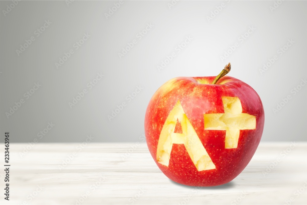 Photo of red apple with A+ on the school desk