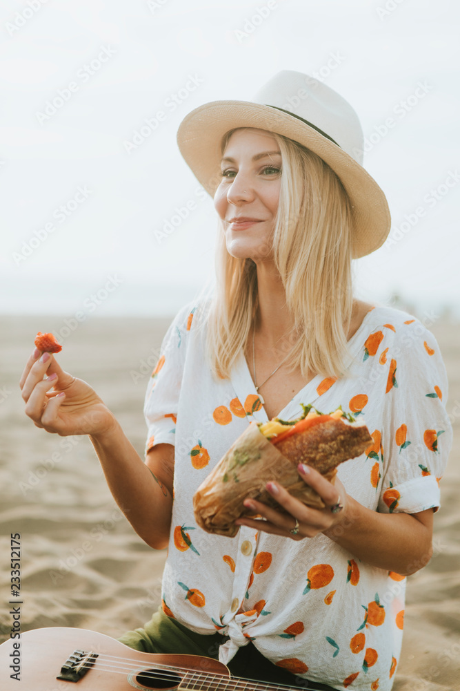 海滩野餐时吃三明治的女人