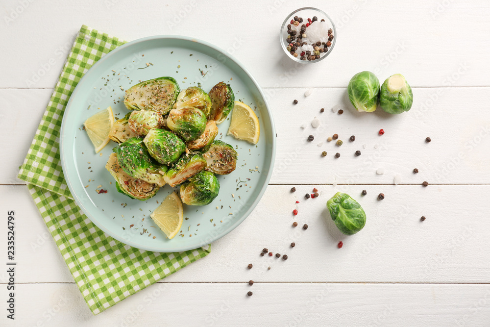 Plate with delicious roasted Brussels sprouts on white wooden table, top view