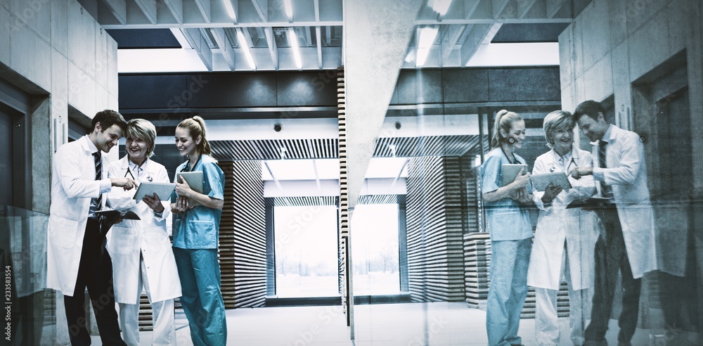 Medical team discussing over digital tablet in corridor