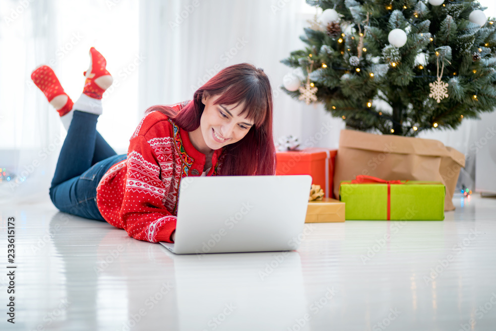 Young woman using laptop next to xmas tree, Christmas shopping online