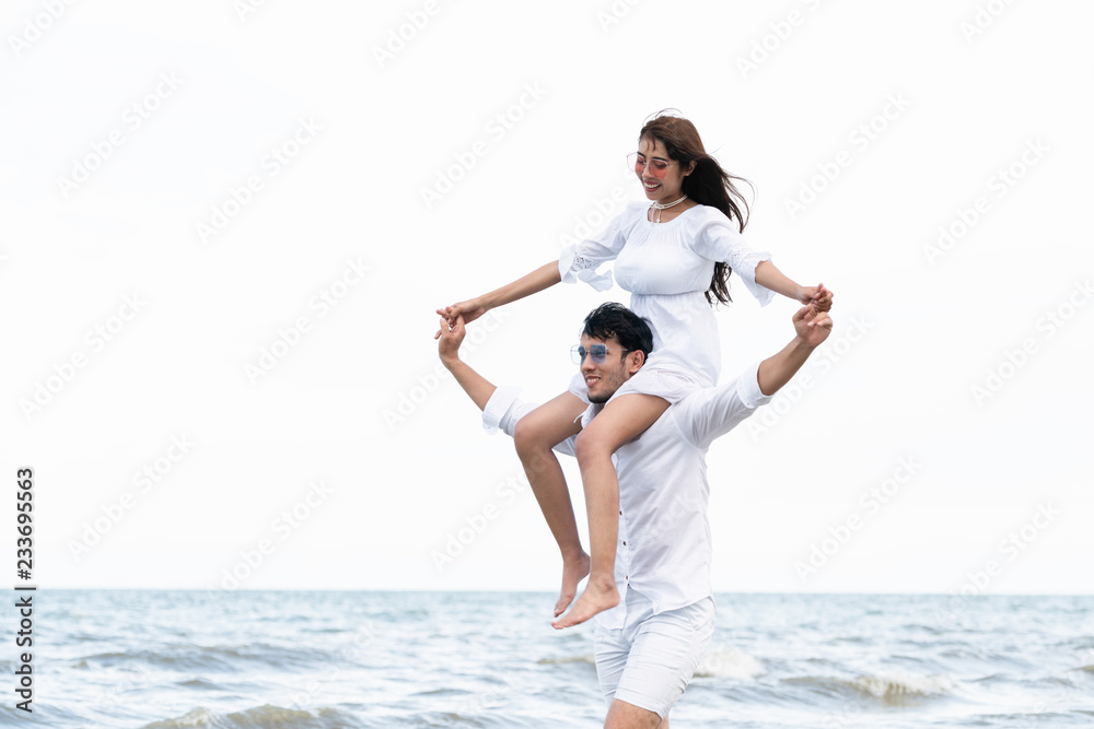 Happy couple going honeymoon travel on tropical sand beach in summer.