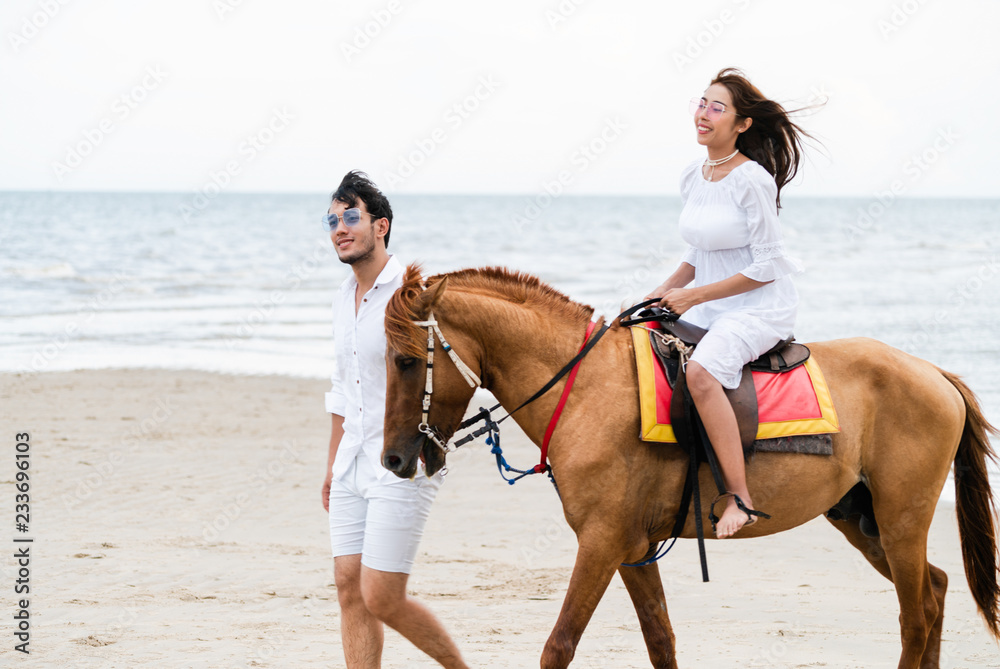 这对年轻夫妇暑假去海滩骑马度蜜月。