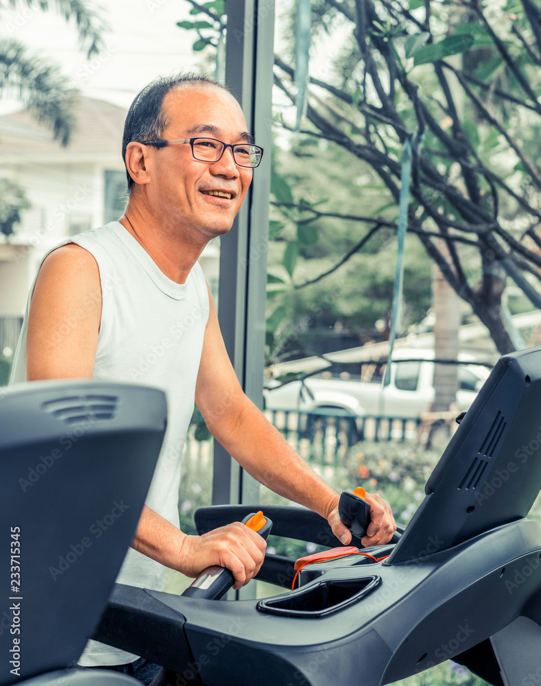 Senior man exercise on treadmill in fitness center. Mature healthy lifestyle.