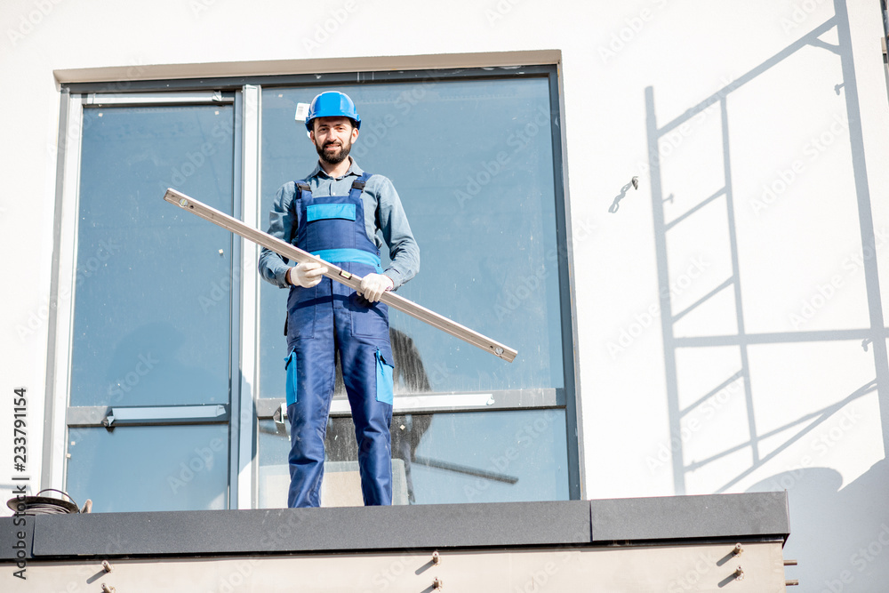 一位身穿制服的建筑工人的肖像，与水平面站在建筑中一栋新房子的阳台上