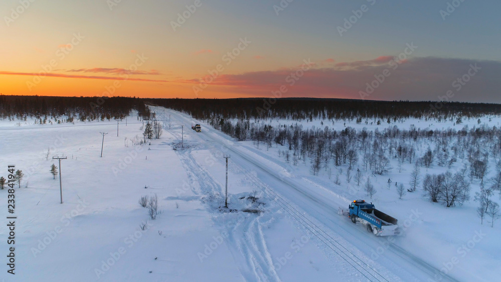 航空航天：扫雪机在森林中行驶和犁过被雪覆盖的高速公路