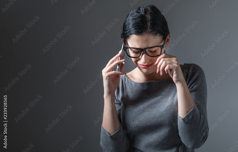 一名年轻女子在灰色背景下与她通话