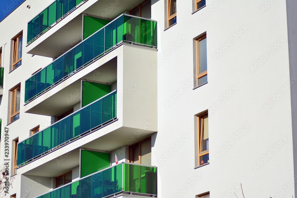 Fragment of a facade of a building with windows and balconies. Modern home with many flats.