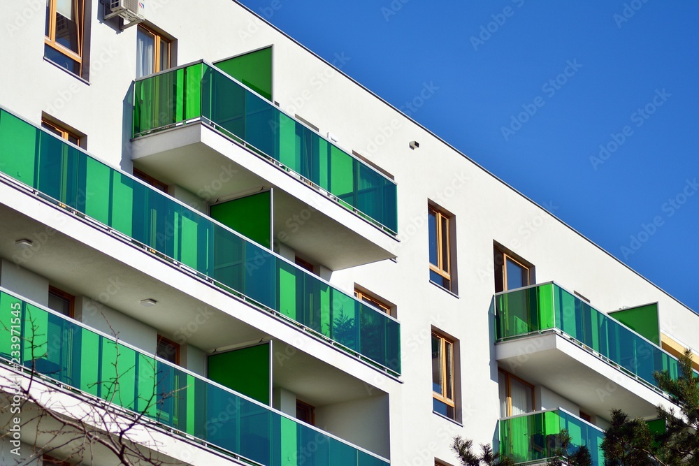 Fragment of a facade of a building with windows and balconies. Modern home with many flats.